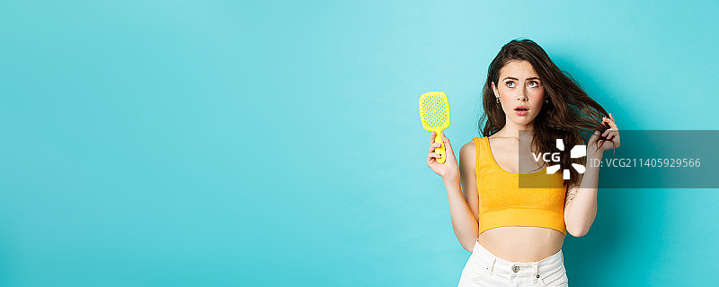 年轻女人担心头发状况，展示着刷子图片素材
