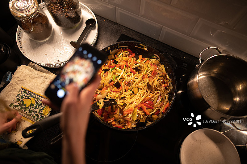 年轻女人在家中厨房准备食物时使用手机，波兰图片素材