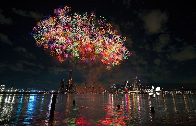 低角度拍摄夜空中河流上的烟花表演图片素材