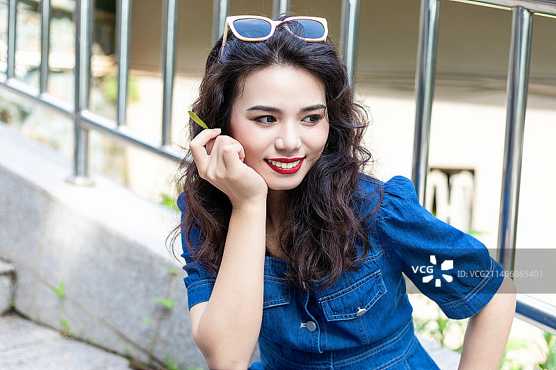 户外一个穿牛仔裙的卷发美女图片素材