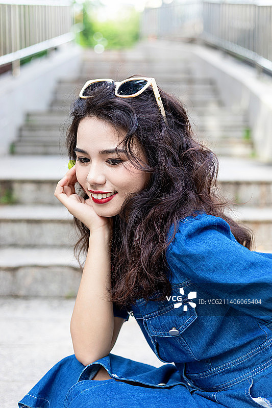 户外一个穿牛仔裙的卷发美女图片素材