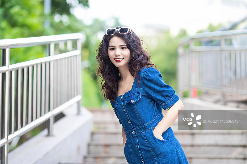 户外一个穿牛仔裙的卷发美女图片素材