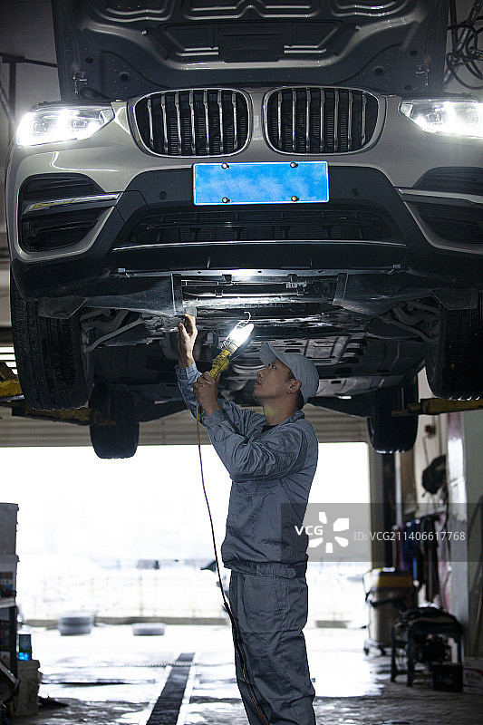 汽车修理工给汽车底盘做检修图片素材
