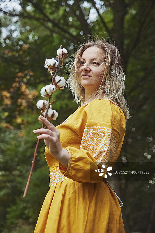 身穿刺绣连衣裙的乌克兰美丽女人手持棉花枝图片素材