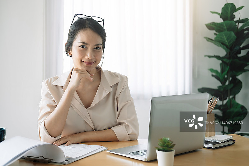 女商人拿着笔记本电脑在文件上查看清单图片素材