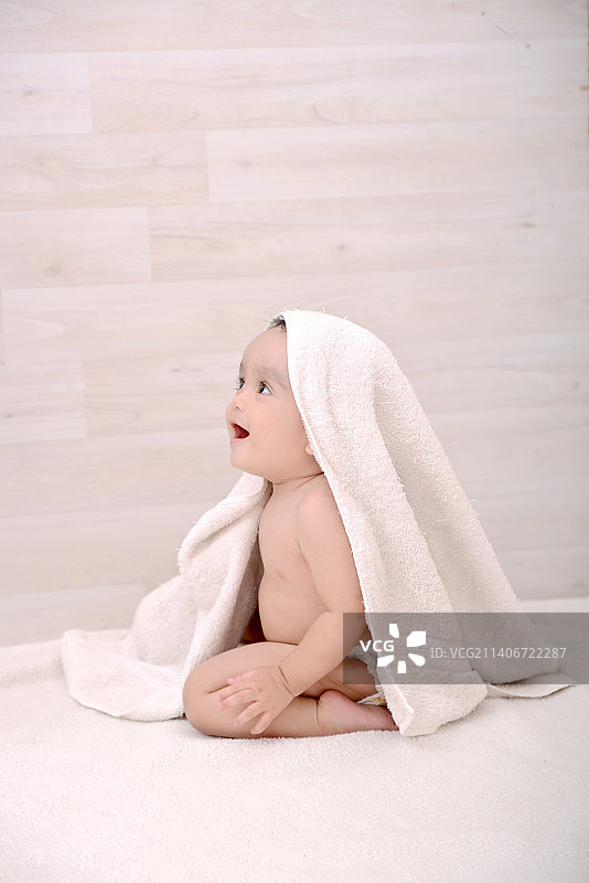 裹着毛巾坐在家中床上的可爱男婴（印度尼西亚）图片素材