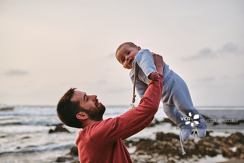 年轻的单亲爸爸抱着宝宝在海滩上玩耍图片素材