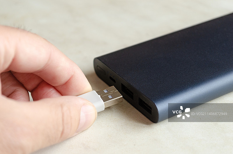 男子将USB线插入充电宝为移动设备充电图片素材