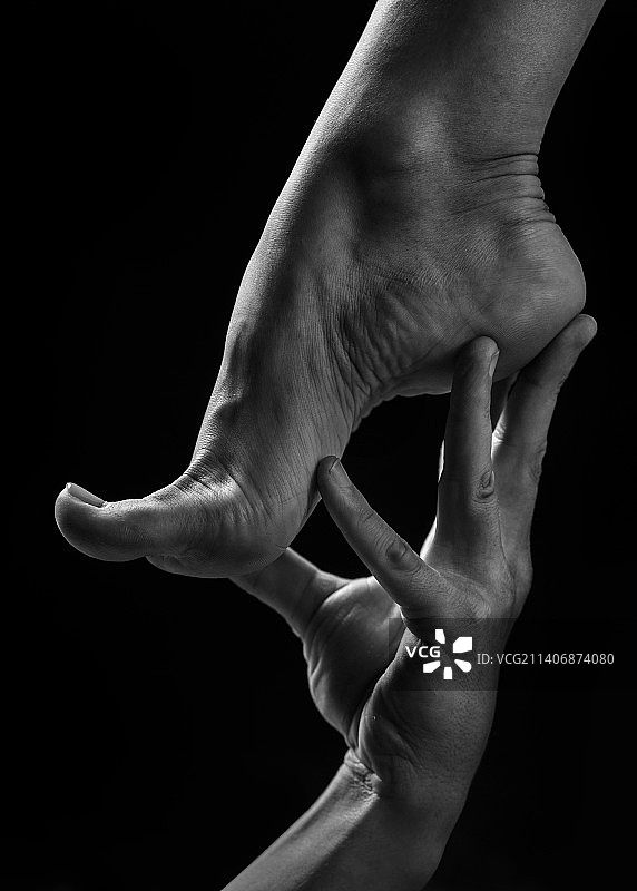 女人在黑色背景下手持脚的局部图图片素材