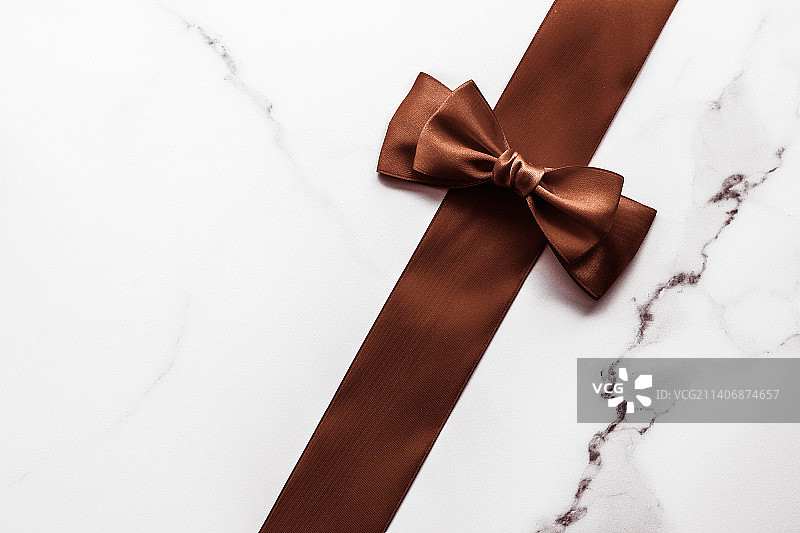 大理石背景上的巧克力色丝带，平铺拍摄图片素材
