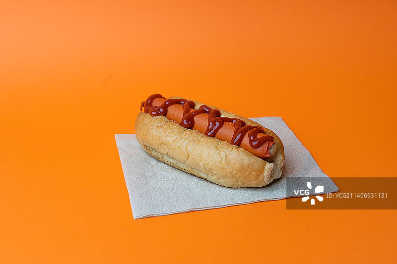 橙色背景下带酱汁的热狗特写图片素材