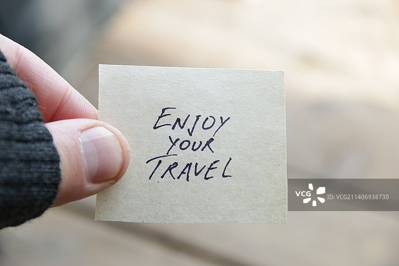 手持写有“旅途愉快”的标签图片素材