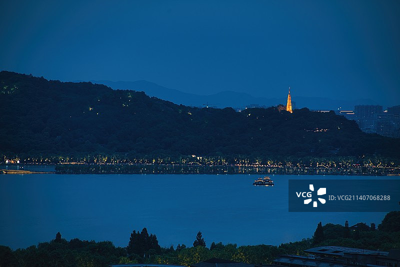 杭州西湖夜晚亮灯的白堤、断桥和保俶塔，湖上的像建筑的是游船图片素材