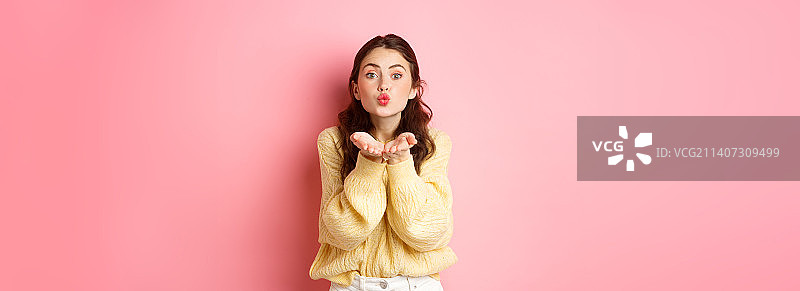 发送飞吻的可爱年轻女子，浪漫地抛媚眼图片素材