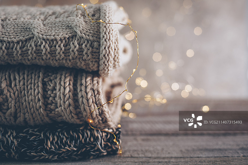 木质背景上舒适的冬季或秋季针织毛衣和花环灯堆图片素材