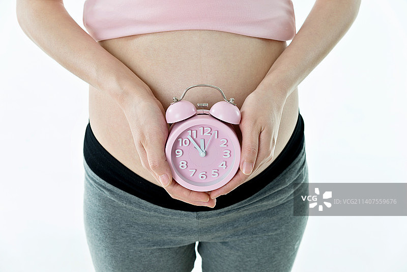 孕妇手上拿着一个闹钟图片素材