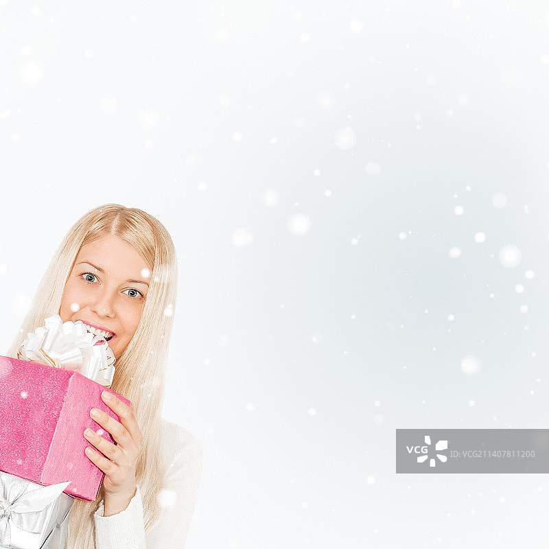 快乐的女人拿着圣诞礼物，银色背景和雪景图片素材