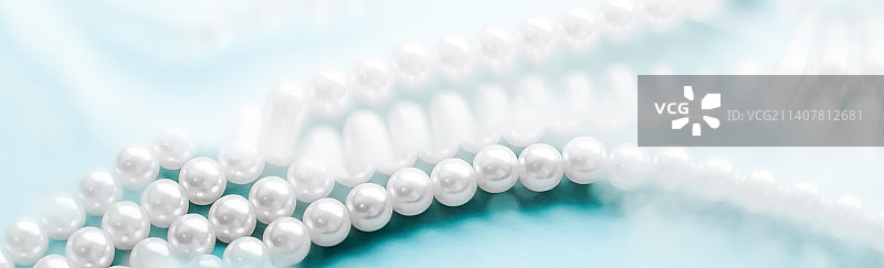 海岸珠宝时尚，蓝色水背景下的珍珠项链图片素材