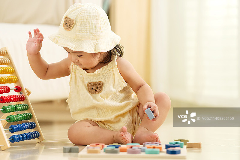 可爱的女宝宝坐在地板上玩耍图片素材