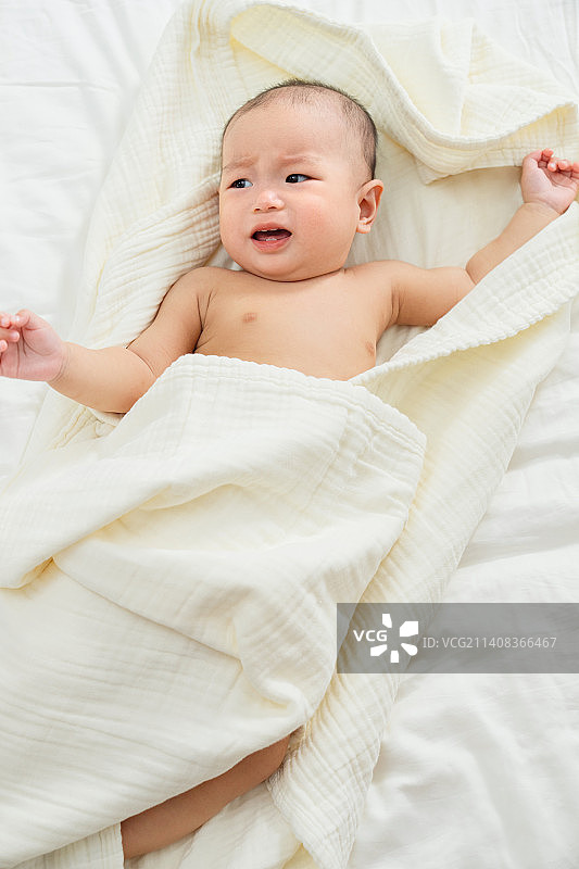 可爱的小宝宝躺在床上玩耍图片素材
