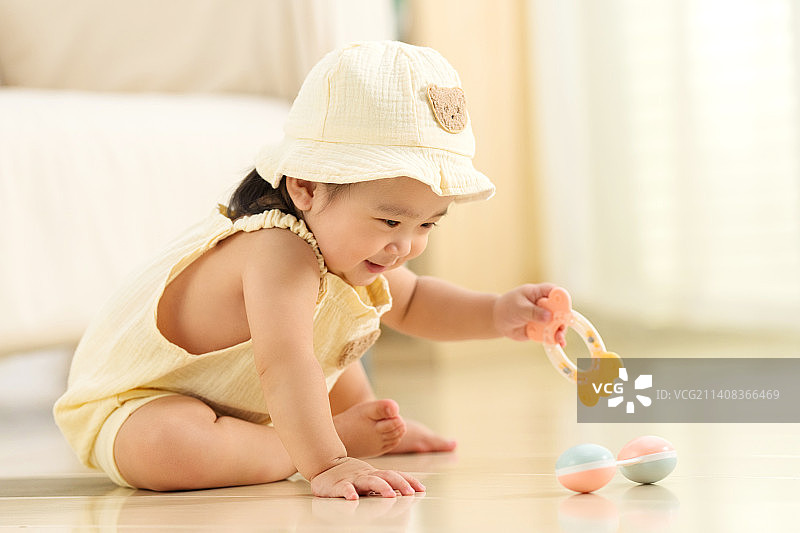可爱的女宝宝坐在地板上玩耍图片素材