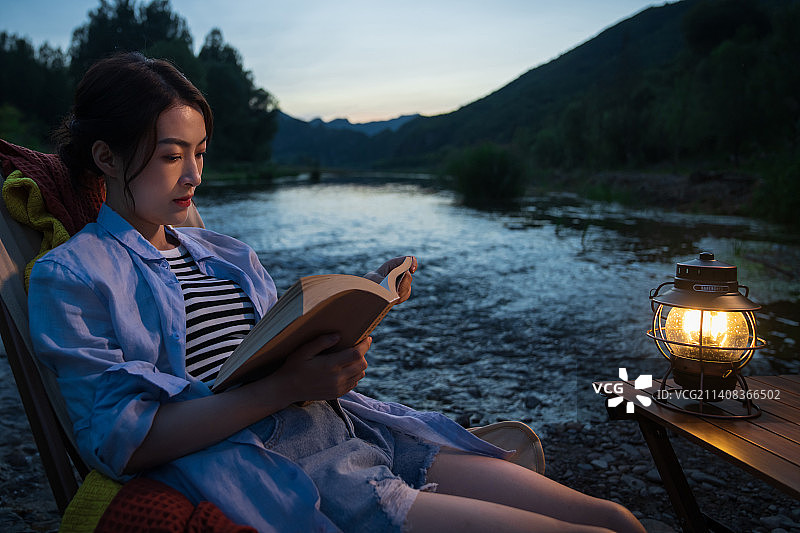 夜晚青年女人在湖边看书图片素材