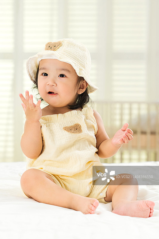 可爱的女宝宝坐在床上玩耍图片素材