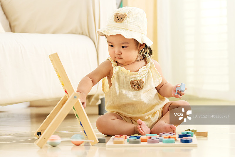 可爱的女宝宝坐在地板上玩耍图片素材