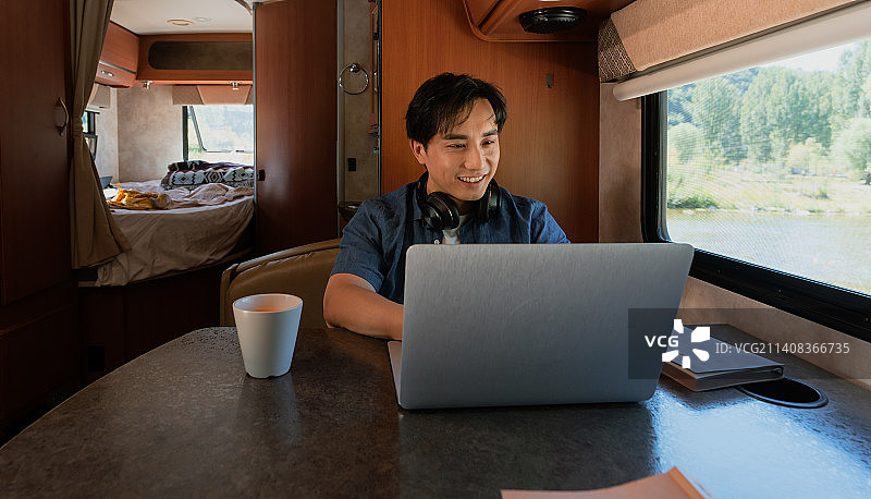 房车内的青年男人使用笔记本电脑图片素材