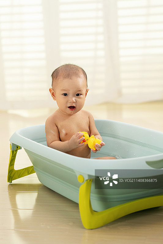 可爱宝宝坐在浴盆里洗澡图片素材