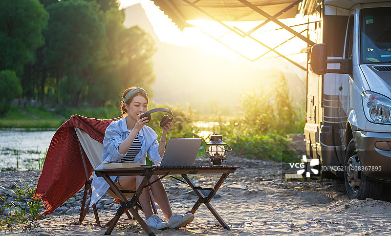 房车旁的青年女人使用笔记本电脑图片素材