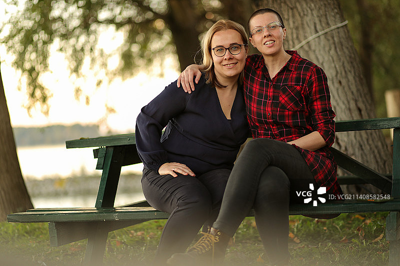 两位年轻女子坐在塞尔维亚公园的长椅上图片素材