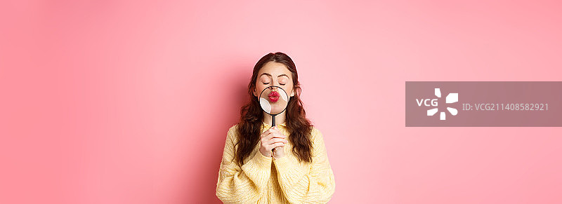 可爱浪漫的年轻女人用放大镜放大嘴唇图片素材