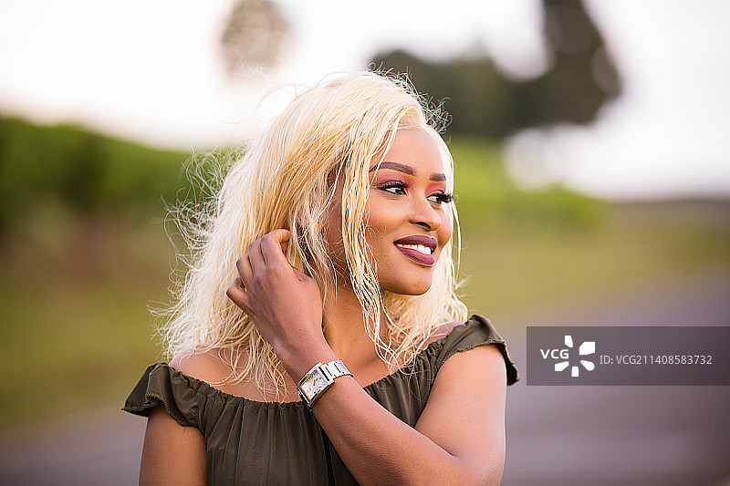 微笑的年轻女人站在内罗毕户外，看向远方图片素材