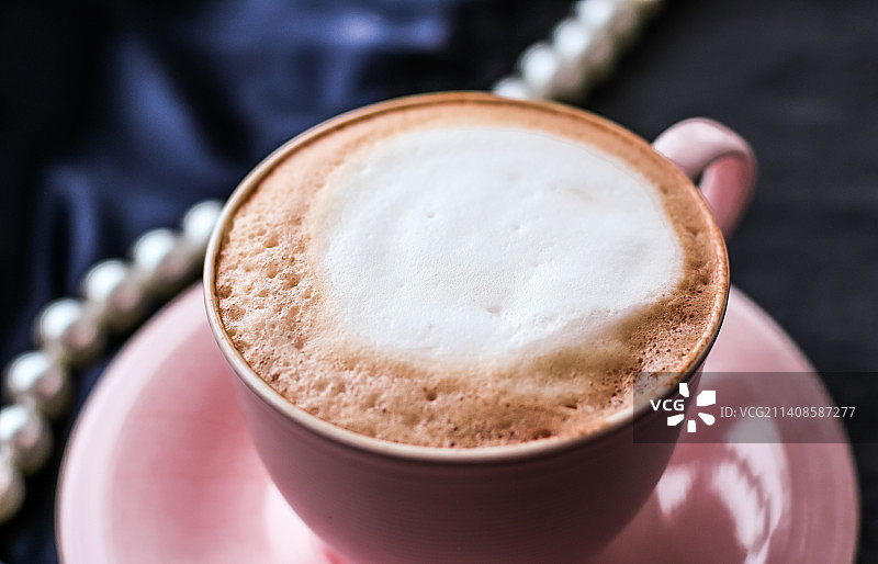 丝绸面料上的卡布奇诺和珍珠饰品，奢华咖啡馆图片素材