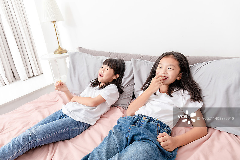 两个中国小女孩在家里吃糖果图片素材