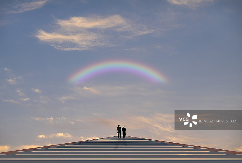 傍晚时分，站在桥头看海的一对老年夫妻图片素材