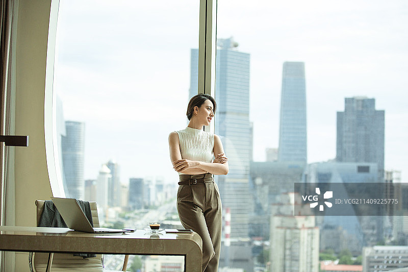 女商人站在酒店房间窗边看风景图片素材