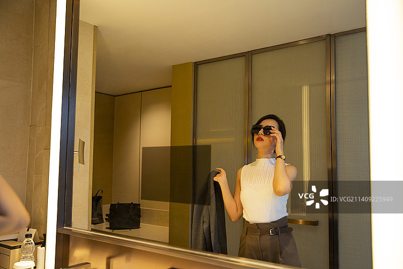 商务女子在酒店房间的卫生间照镜子装扮自己图片素材