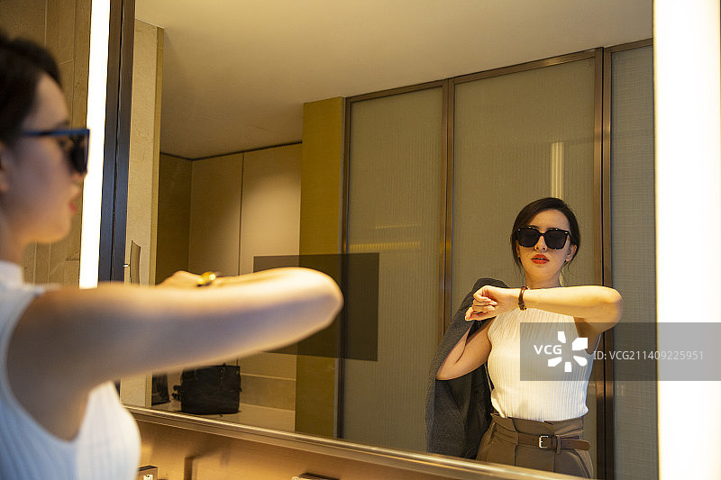 商务女子在酒店房间的卫生间装扮自己、看手表图片素材
