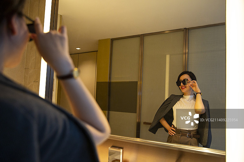 商务女子在酒店房间的卫生间照镜子装扮自己图片素材