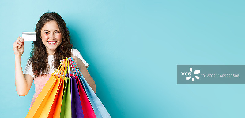 面露微笑的年轻满意女人展示塑料信用卡图片素材