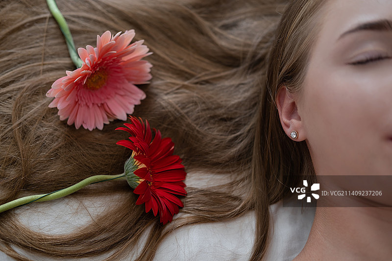 手持粉色和红色菊花的美丽年轻女子图片素材