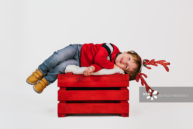 在圣诞节期间躺在白色背景上的快乐男孩，西班牙巴利亚多利德图片素材