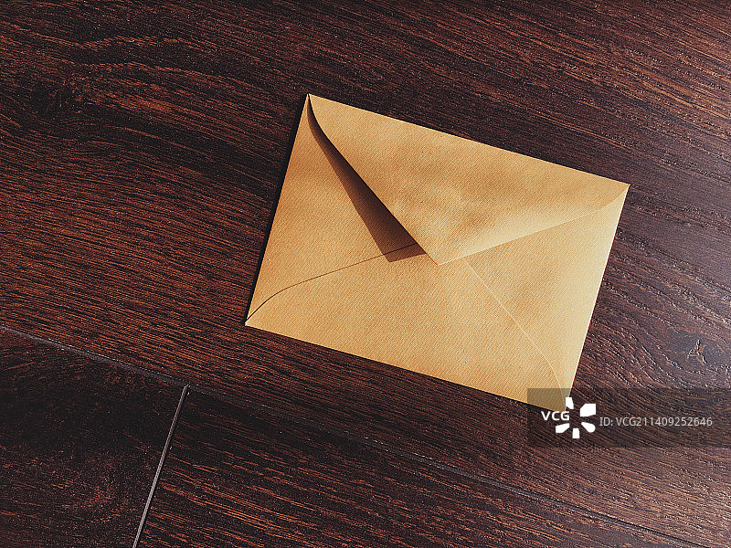 木质背景上的金色复古信封，用于时事通讯和消息传递图片素材
