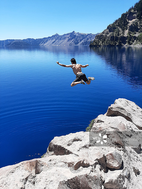 男人在清澈的蓝天下在湖中跳跃图片素材
