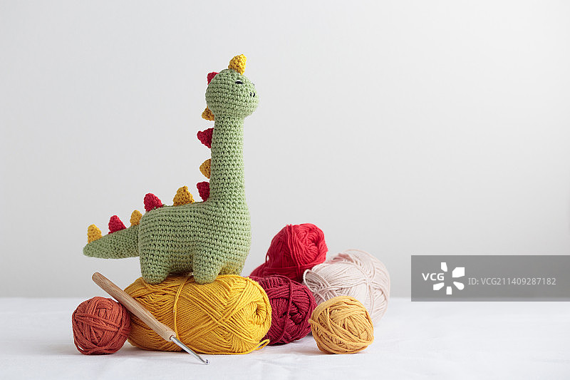 白色背景上的可爱绿色钩针恐龙和纱线图片素材