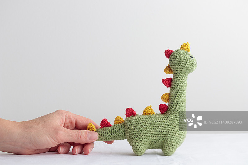 白色背景上的钩针编织的可爱绿色恐龙图片素材