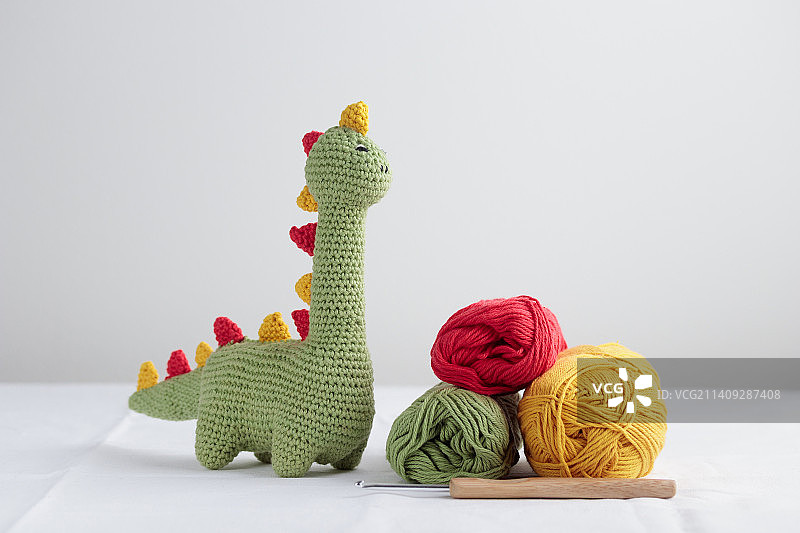 白色背景上的可爱绿色钩针恐龙和纱线图片素材