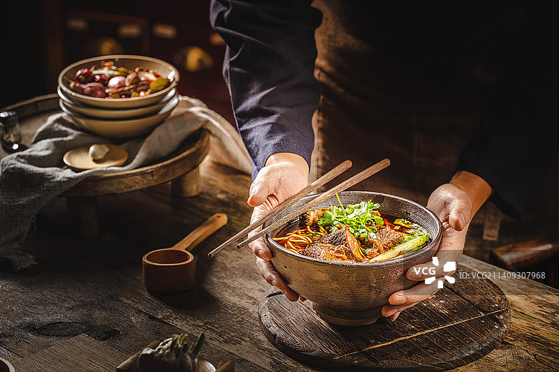 中式复古背景 美食 暗调 老木桌 牛肉面 端着一碗面 大坨牛肉图片素材